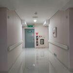 Quiet hospital corridor leading to emergency exit, features clean and minimal design.